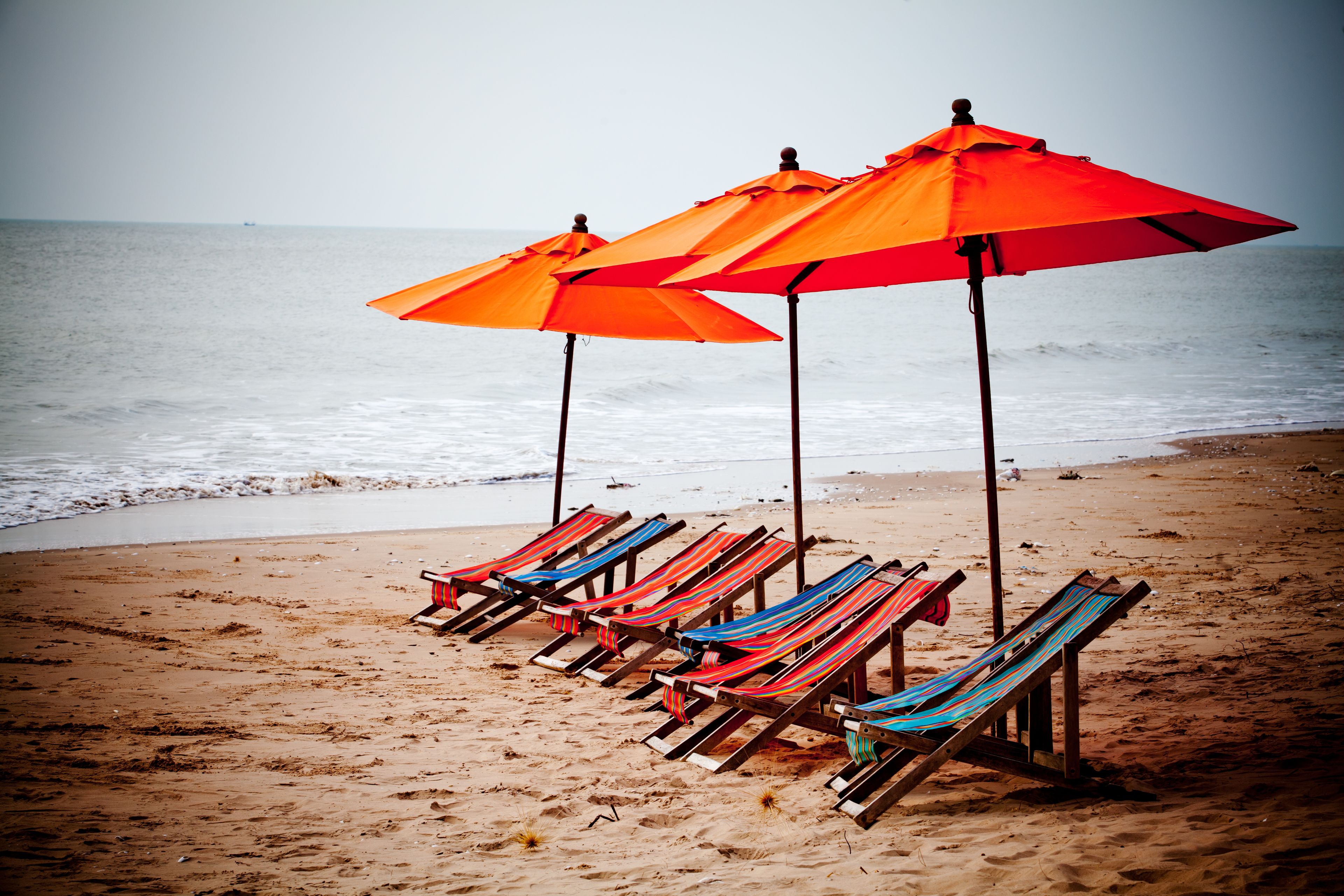 Beach chairs and umbrellas on a sandy beach with the ocean in the background.