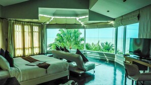 A modern hotel room with a large bed, a sofa, a TV, and a view of the ocean. - Vartika Resovilla KuiBuri Beach Resort and Villas (Prachuap Khiri Khan)
