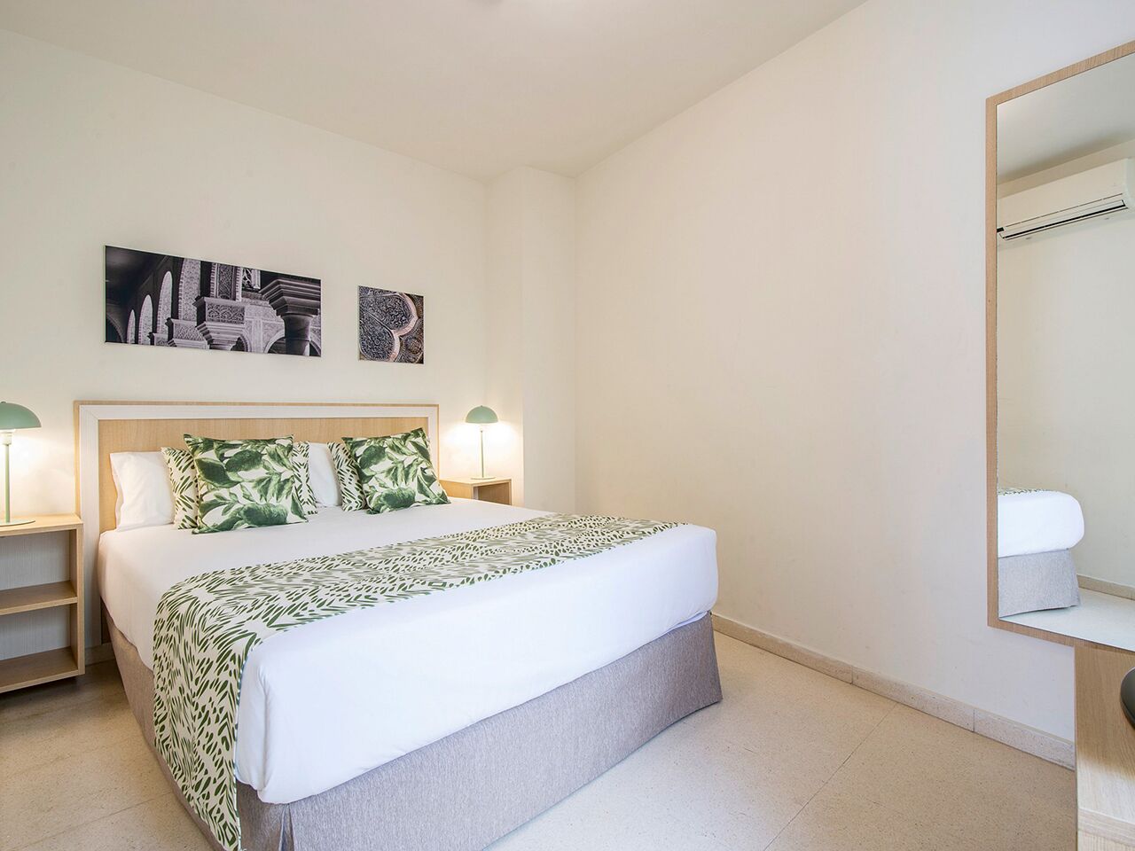 A neatly arranged bedroom with a bed, bedside tables, and a mirror.