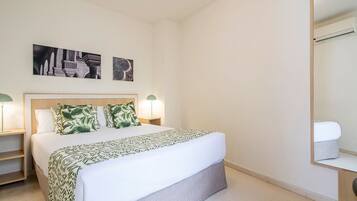 A neatly arranged bedroom with a bed, bedside tables, and a mirror.