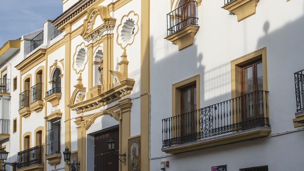 Un edificio histórico con balcones ornamentados y una entrada central.