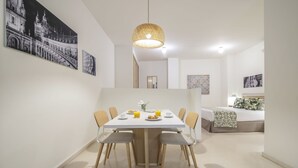 Un comedor moderno con una mesa blanca, sillas y una lámpara colgante.