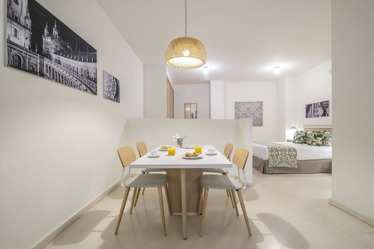 A modern dining area with a white table, chairs, and a hanging light fixture.