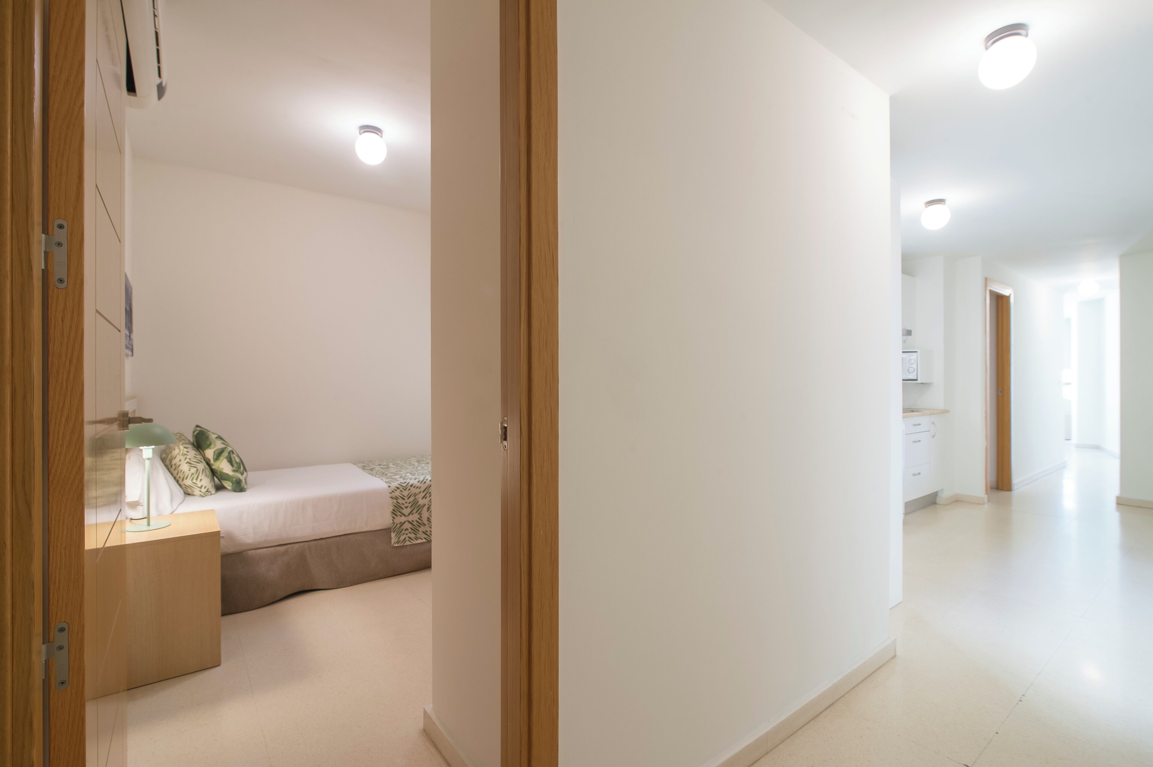 Une chambre moderne et bien éclairée, avec un lit, une table de chevet et une lampe.