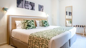 Un dormitorio ordenado con una cama grande, una mesita de noche, un espejo y decoración en la pared.