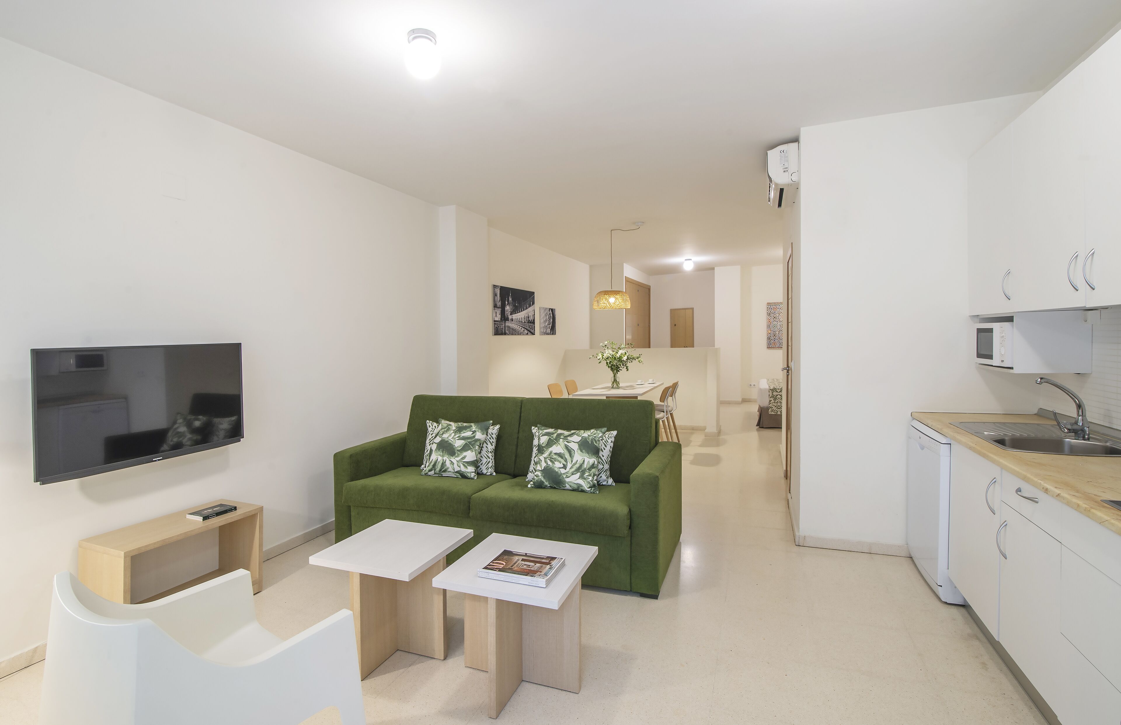 A modern living room with a green sofa, white coffee table, and a flat-screen TV.