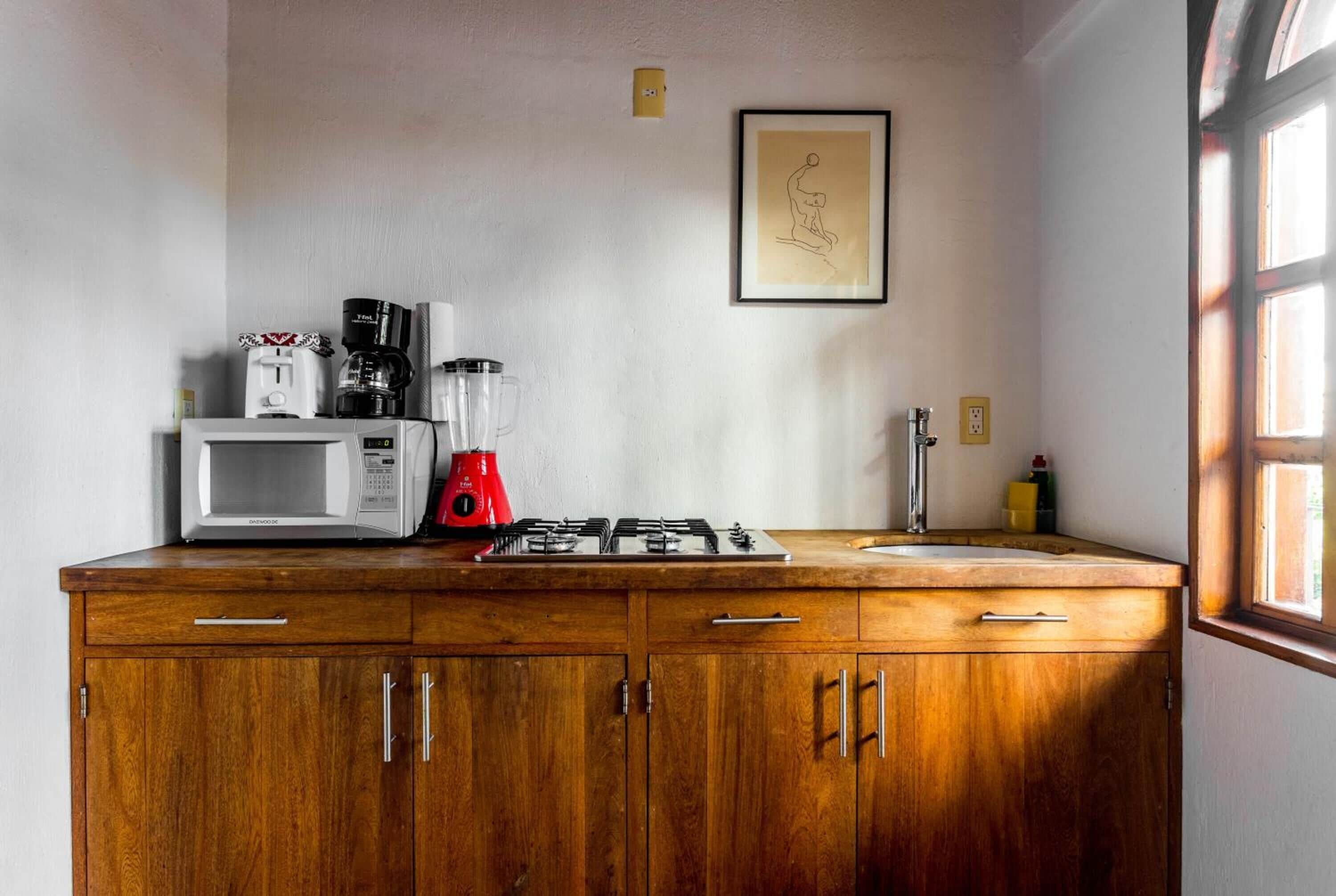 A kitchen with wooden cabinets, a microwave, a red coffee maker, and a gas stove.