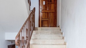 A staircase with beige tiles and a brown metal railing leading to a wooden door. - Olas Altas Suites (Puerto Vallarta)