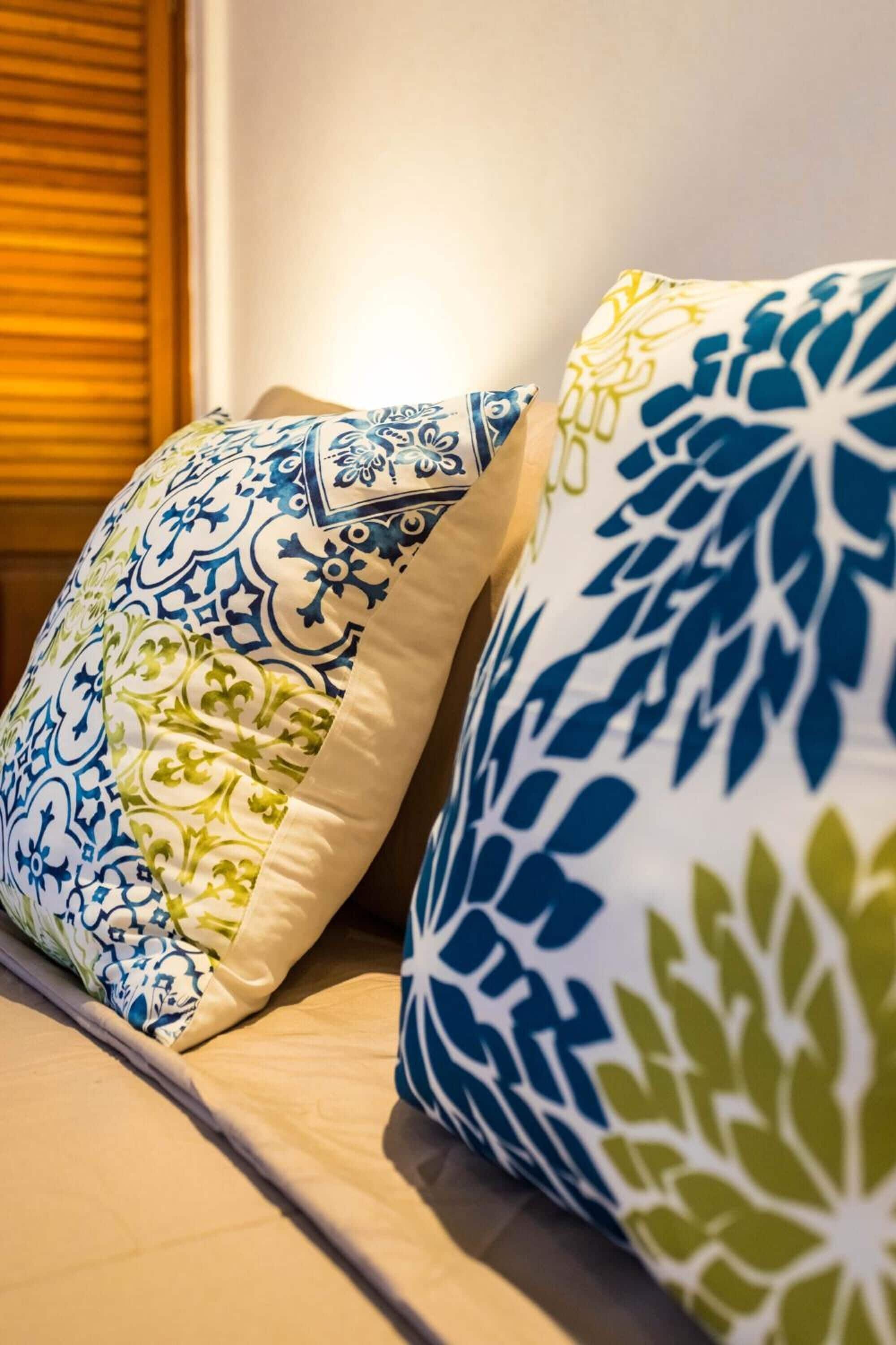 A bed with two decorative pillows featuring intricate patterns.