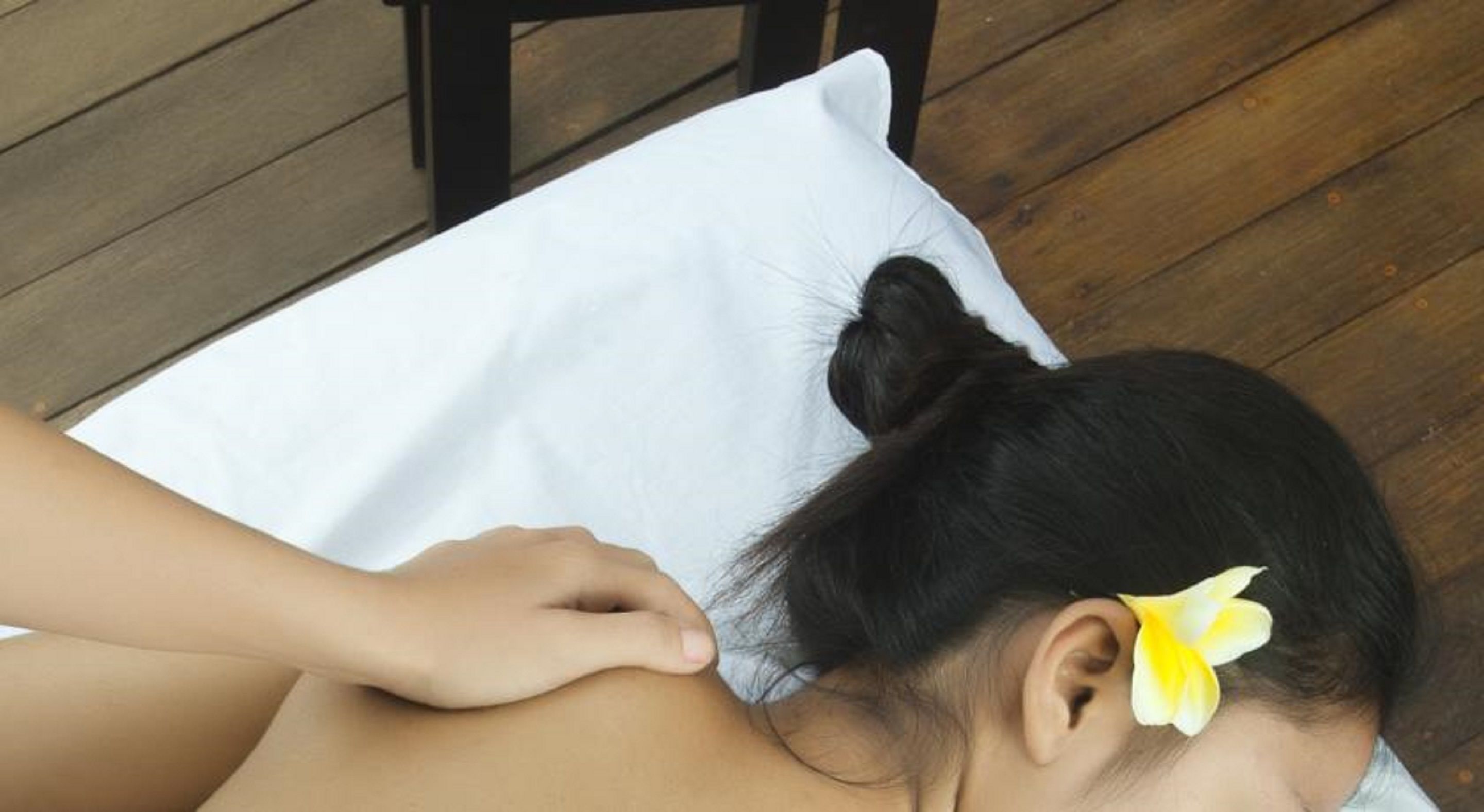 A person receiving a massage on a wooden deck.