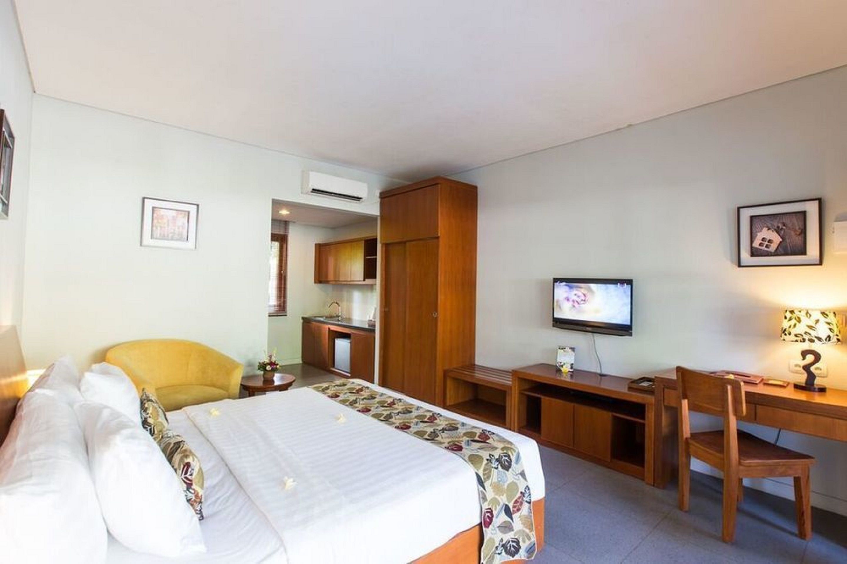 A hotel room with a bed, a desk, a chair, a television, and a wardrobe.