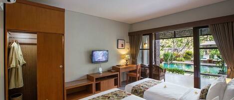 A hotel room with two beds, a desk with a TV, a window with a view of a pool, and a wardrobe.