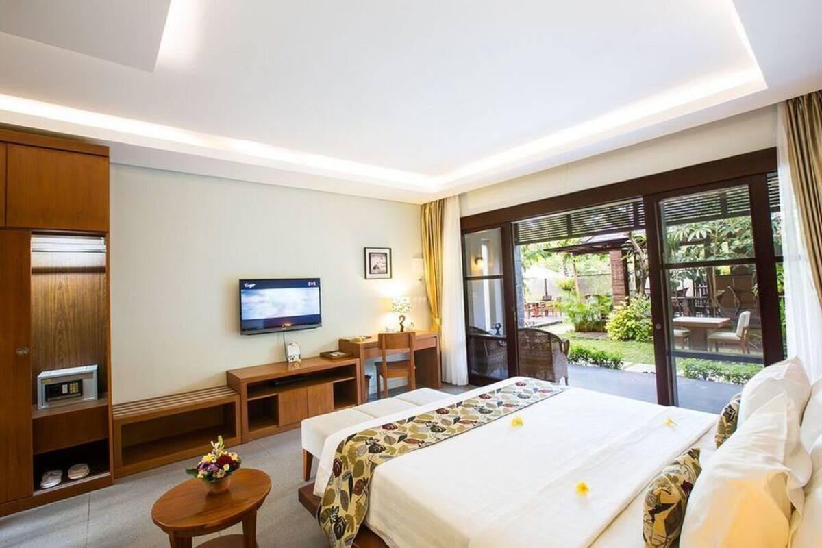 Una camera d'albergo con un letto, una scrivania, una televisione e vista sul giardino.