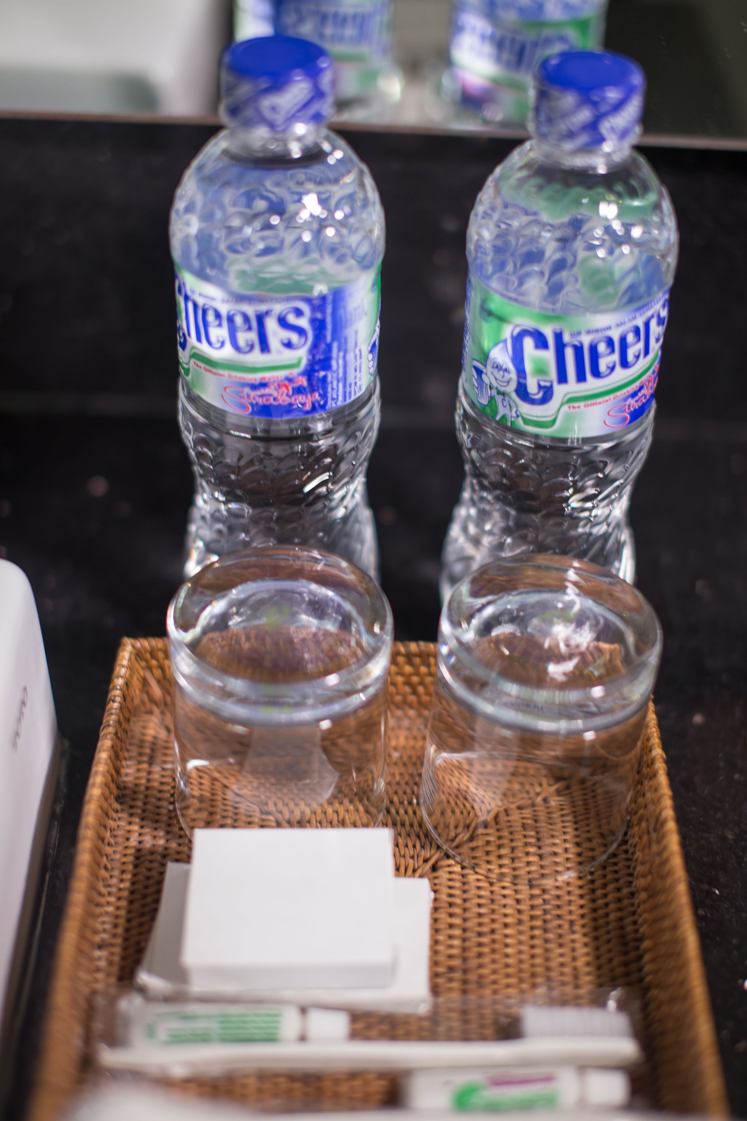 Dos botellas de agua Cheers sobre una bandeja con un objeto blanco y un frasco pequeño.