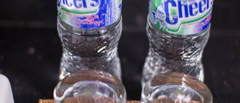 Dos botellas de agua Cheers sobre una bandeja con un objeto blanco y un frasco pequeño.