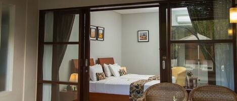 A hotel room with a bed, a sofa, and a small table with a flower vase.