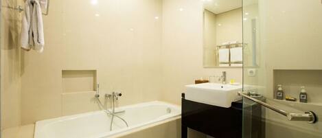 A modern bathroom with a bathtub, a sink, and a glass shower enclosure.