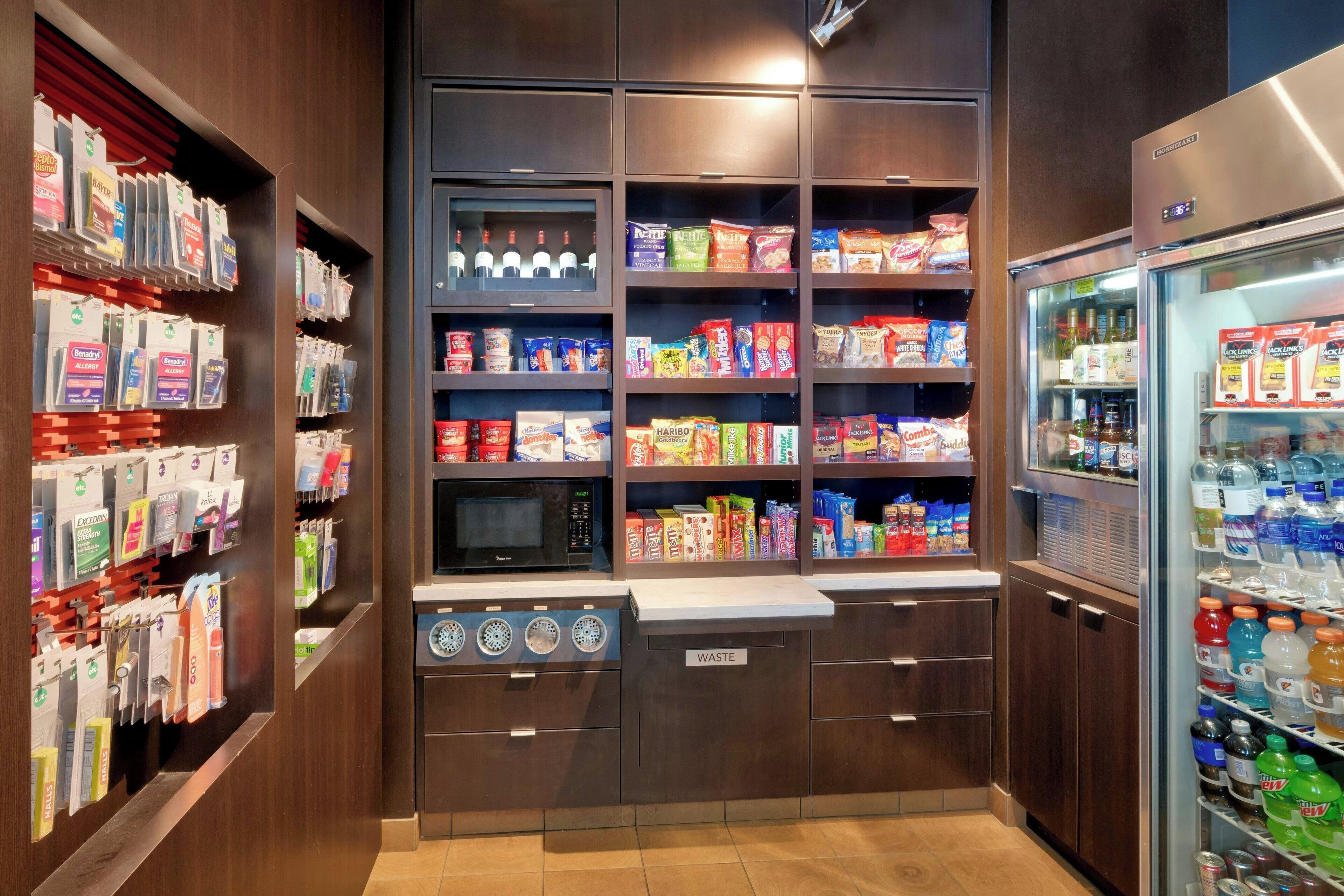 A well-organized self-service kiosk with various packaged goods, a microwave, and a waste bin.