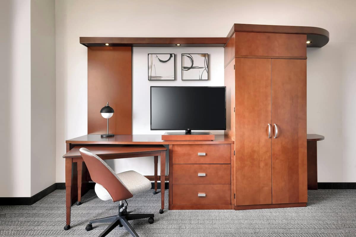 A modern office space with a desk, chair, television, and built-in cabinet.