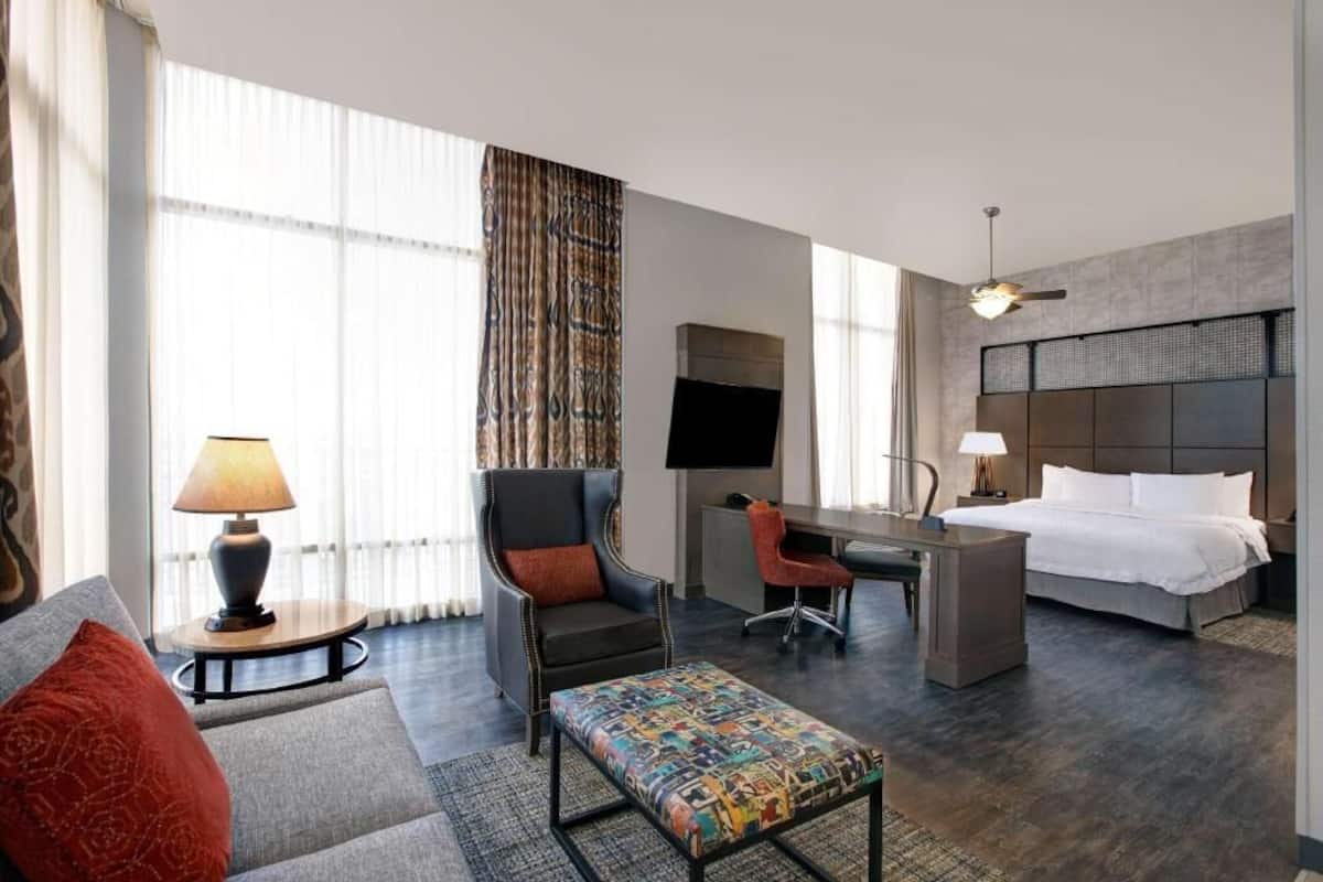 A hotel room with a bed, desk, chair, and a sofa.