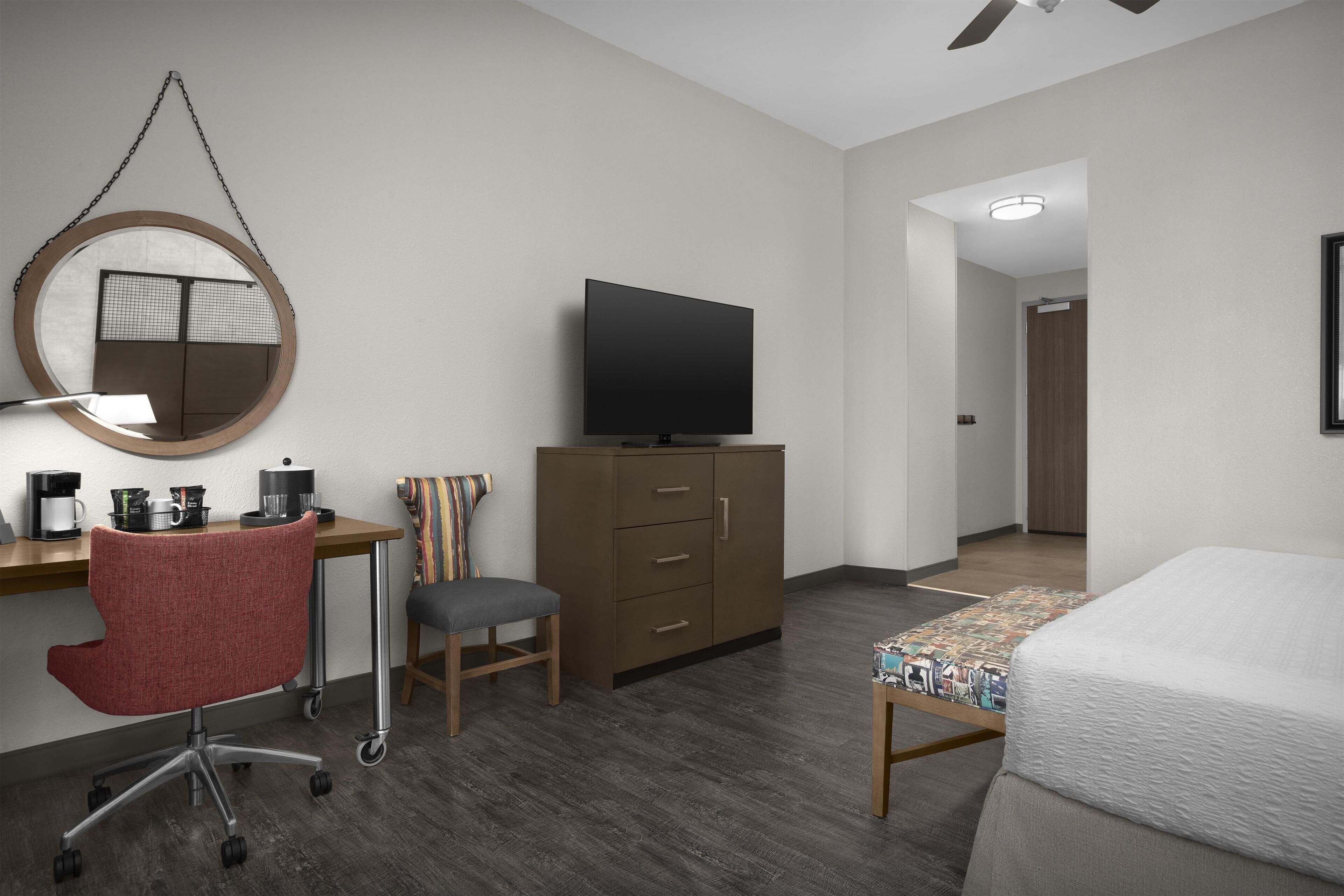 A hotel room with a desk, chair, television, wardrobe, and bed.
