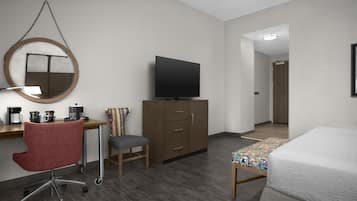 Une chambre d’hôtel équipée d’un bureau, d’une chaise, d’une télévision, d’une armoire et d’un lit.