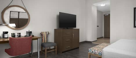A hotel room with a desk, chair, television, wardrobe, and bed.