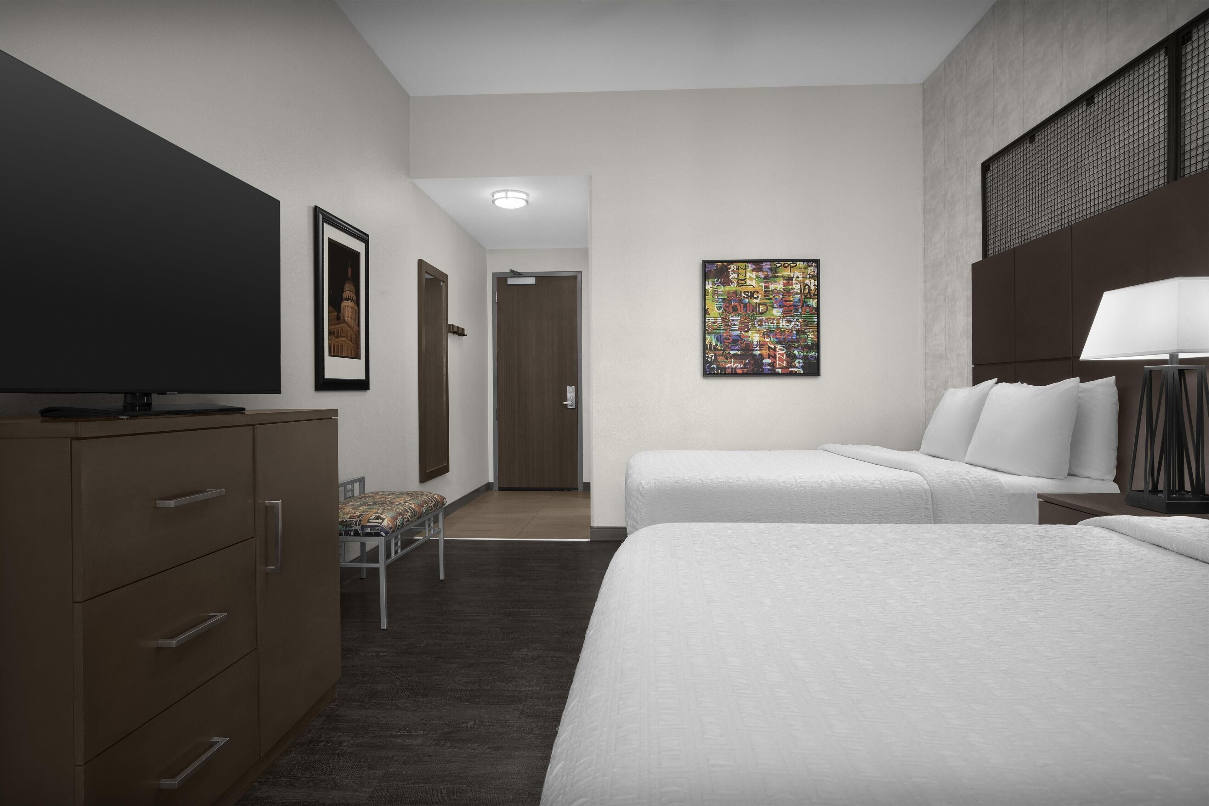 Une chambre d’hôtel avec deux lits, une télévision, un bureau et une chaise.