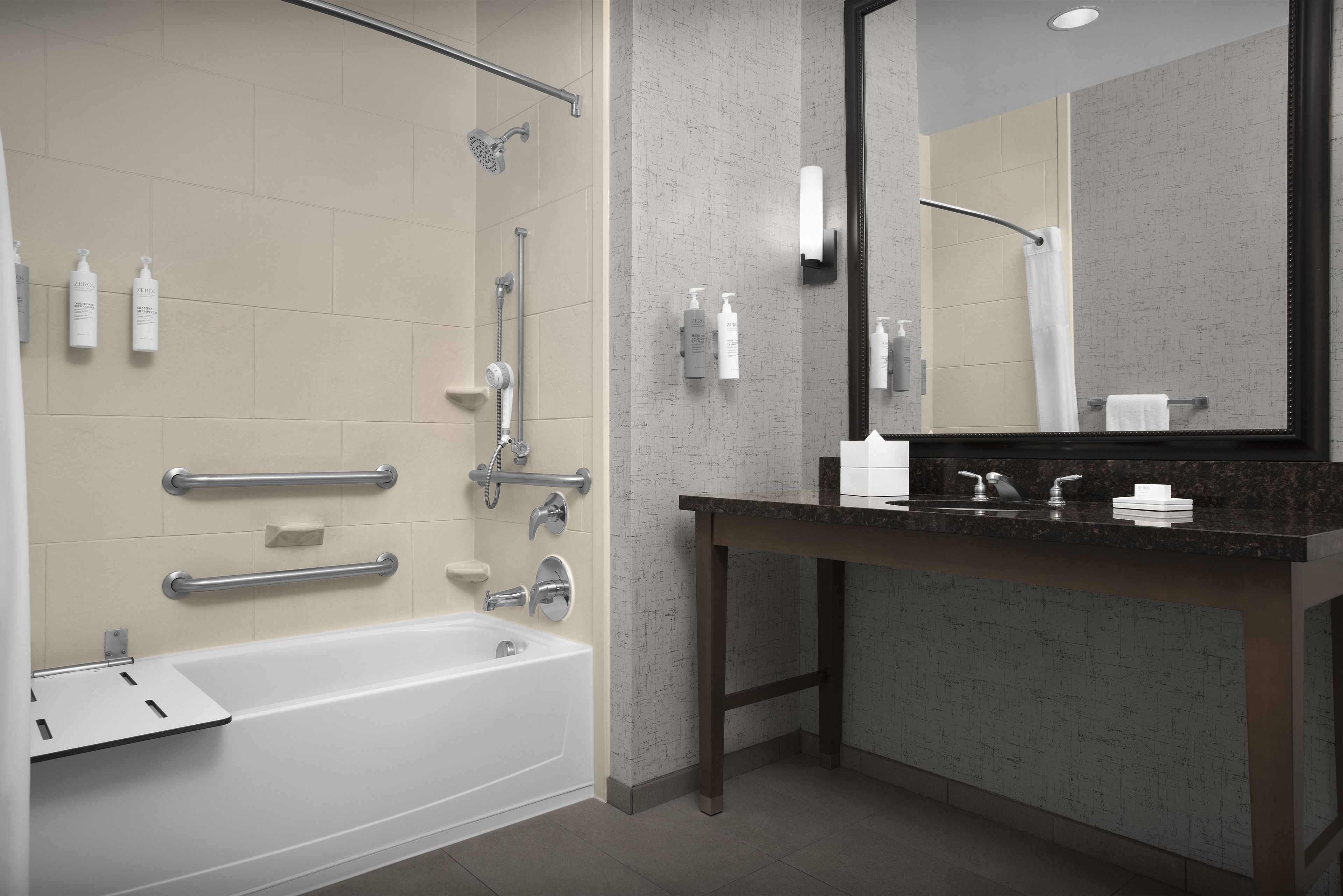 A modern bathroom with a bathtub, shower, and vanity.
