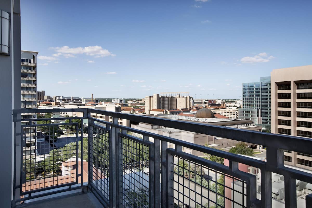 A high-rise building with a view of a cityscape, including various buildings and a clear sky.