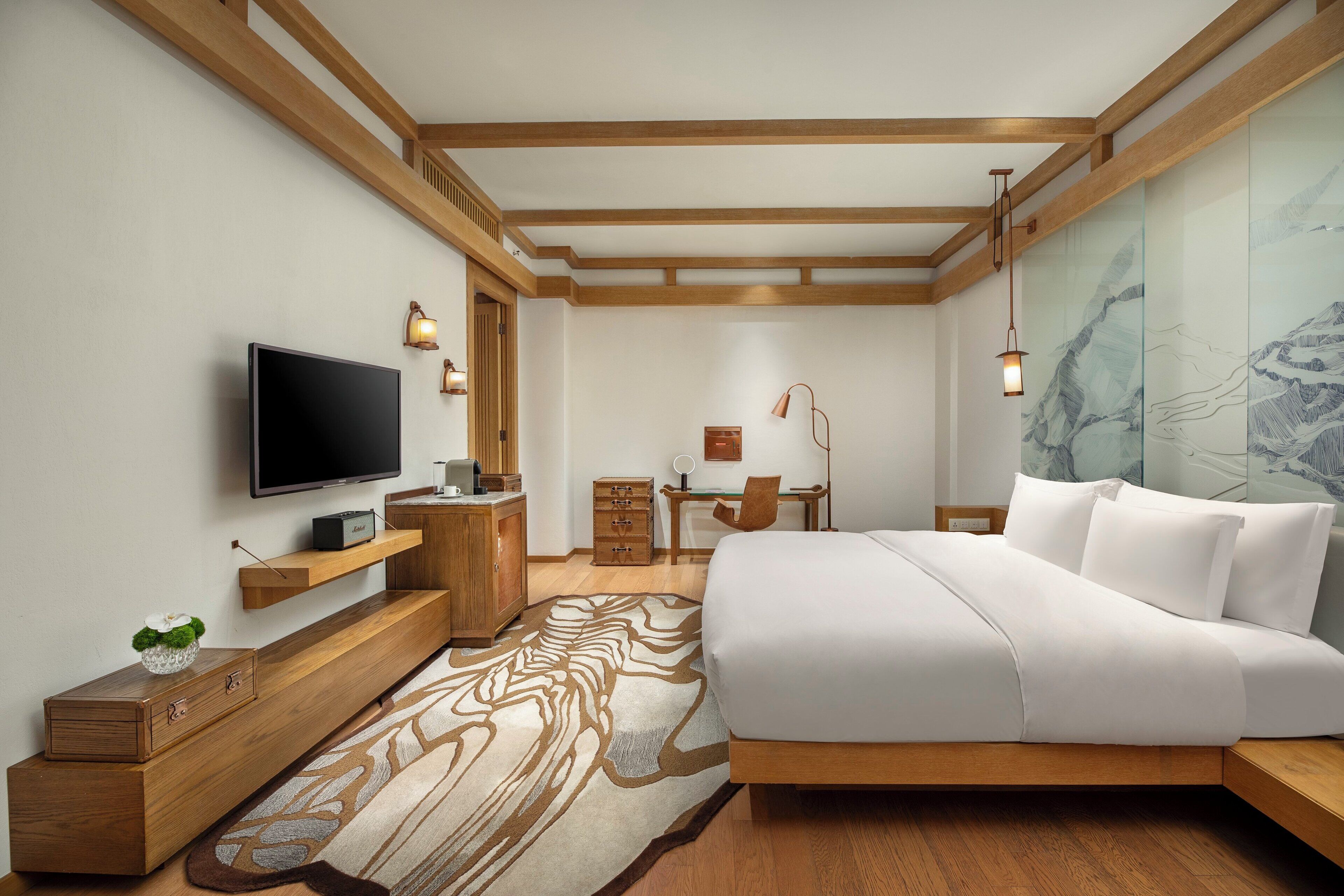 Un dormitorio moderno con cama, televisión, muebles de madera y escritorio.