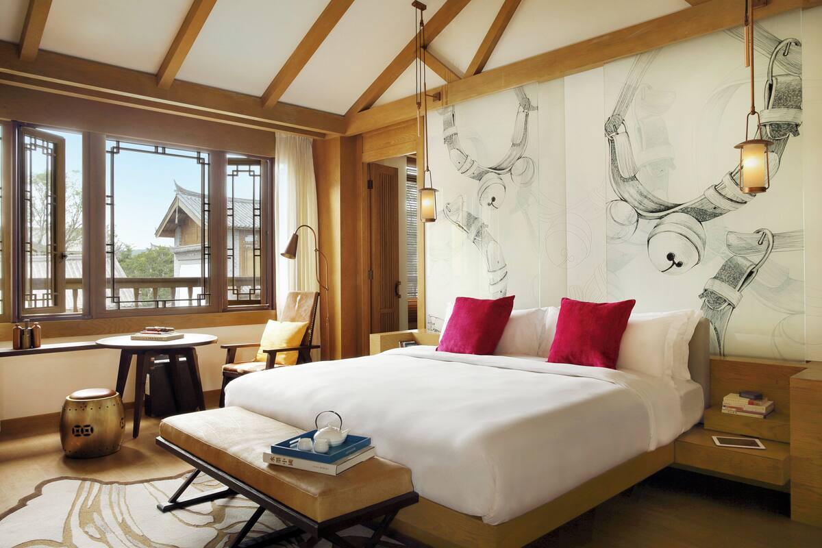 Een slaapkamer met een groot bed, een bureau en een uitzicht door een raam.