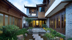 A traditional courtyard with a stone bridge, potted plants, and a water feature. - Hotel Indigo Lijiang Ancient Town by IHG (Lijiang)
