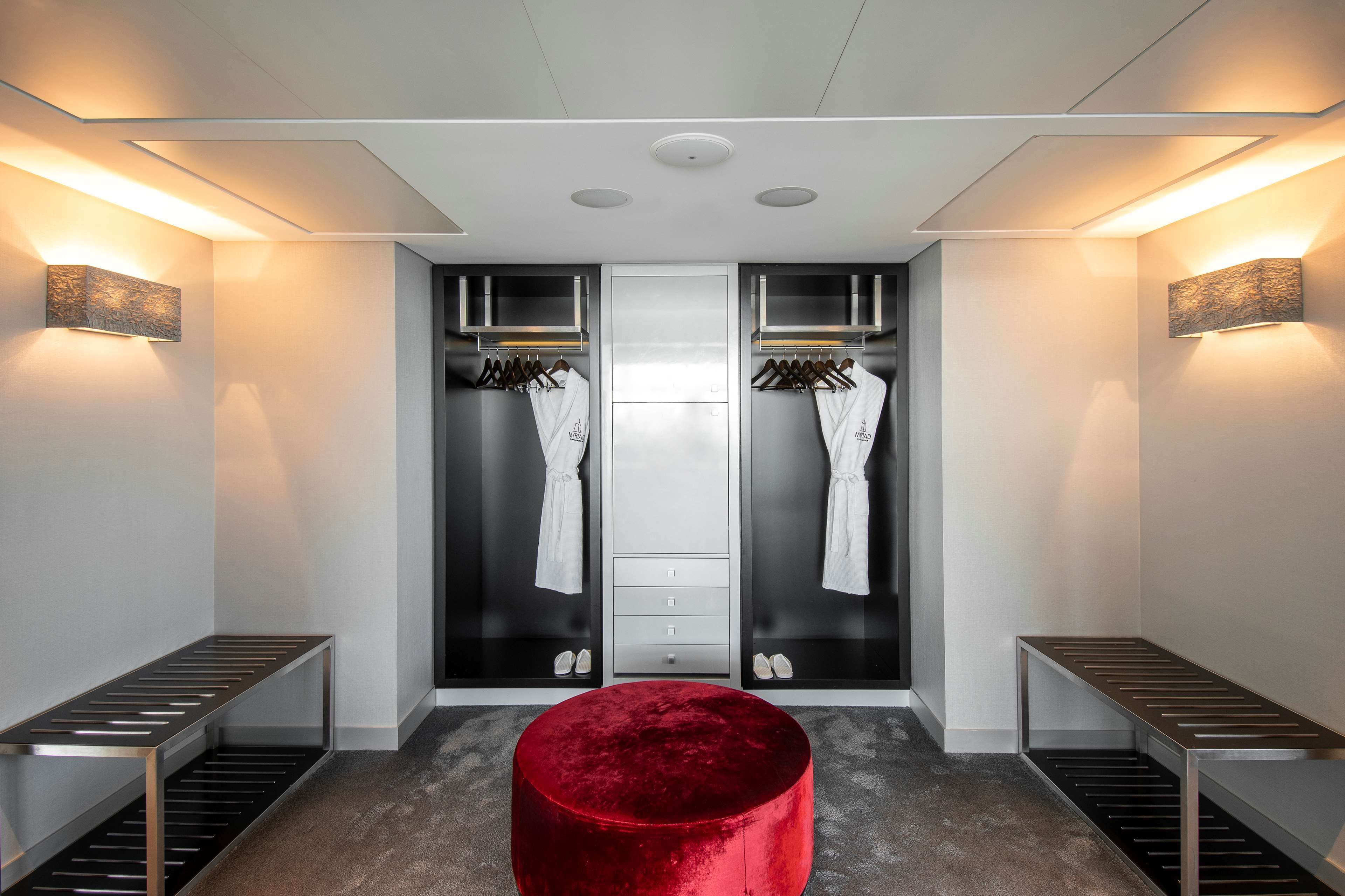 Un baño moderno con tocador, perchero y un reposapiés rojo.