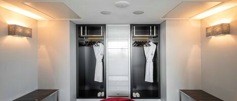 A modern bathroom with a vanity, towel rack, and a red ottoman.