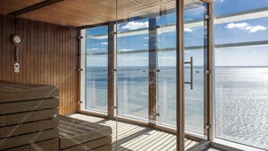 Une pièce avec un plafond en bois, une grande porte vitrée donnant sur une vue sur la mer et un banc en bois.