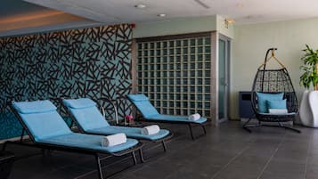 Un área de spa con tres sillones reclinables, una silla colgante y una planta grande en maceta.