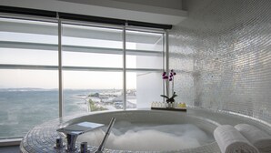 Un spa moderne doté d’une grande baie vitrée, d’un jacuzzi et offrant une vue sur la ville.