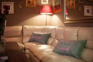A cozy living room with a beige leather sofa, a red floor lamp, and decorative pillows. - Art Rustic Hotel (Chisinau)