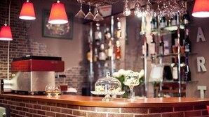 A bar area with a brick counter, a coffee machine, and a display of glasses and bottles. - Art Rustic Hotel (Chisinau)