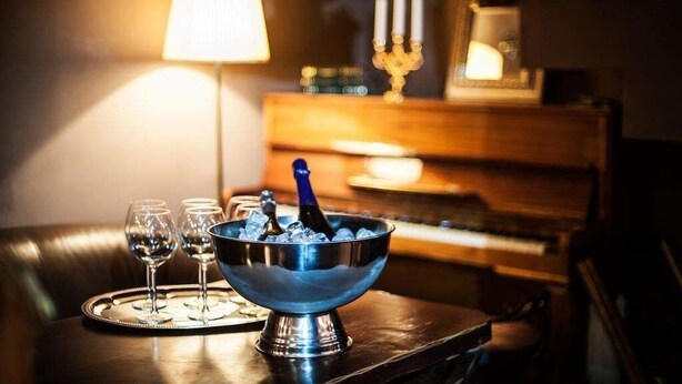 A bar area with a metal bowl containing ice and a bottle, two glasses, and a tray with a candle holder. - Art Rustic Hotel (Chisinau)