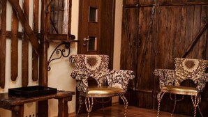Two patterned chairs with a sun design, a wooden bench, and a rustic wooden door. - Art Rustic Hotel (Chisinau)