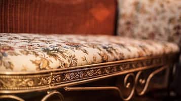 A close-up of a vintage-style sofa with floral upholstery and ornate metal legs.