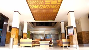 Een hotel lobby met een versierd plafond, een receptiebalie en een zithoek.