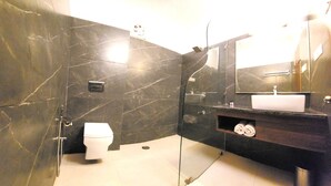 Een badkamer met toilet, wastafel, spiegel en douchehoek.