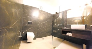 Un baño con inodoro, lavamanos, espejo y zona de ducha.
