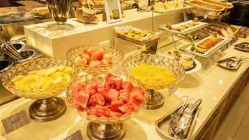 A buffet with various food items including fruits and desserts.