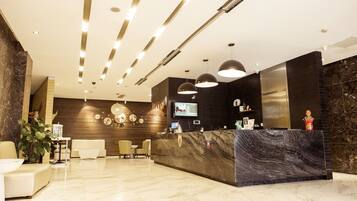 A modern reception area with a marble reception desk, multiple seating options, and a large flat-screen TV.