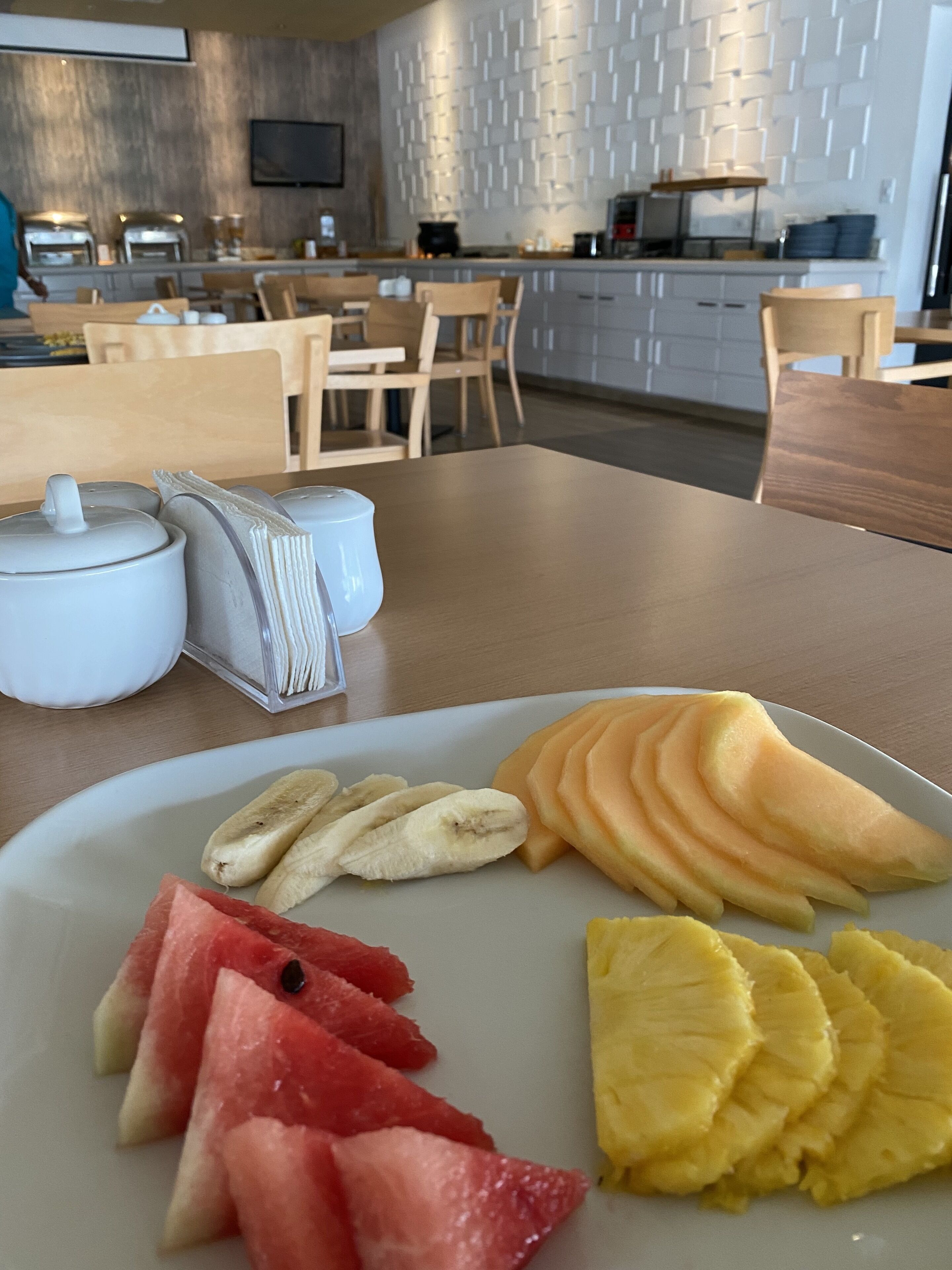 Un plato de desayuno con frutas cortadas y una tetera sobre una mesa en una cocina moderna.