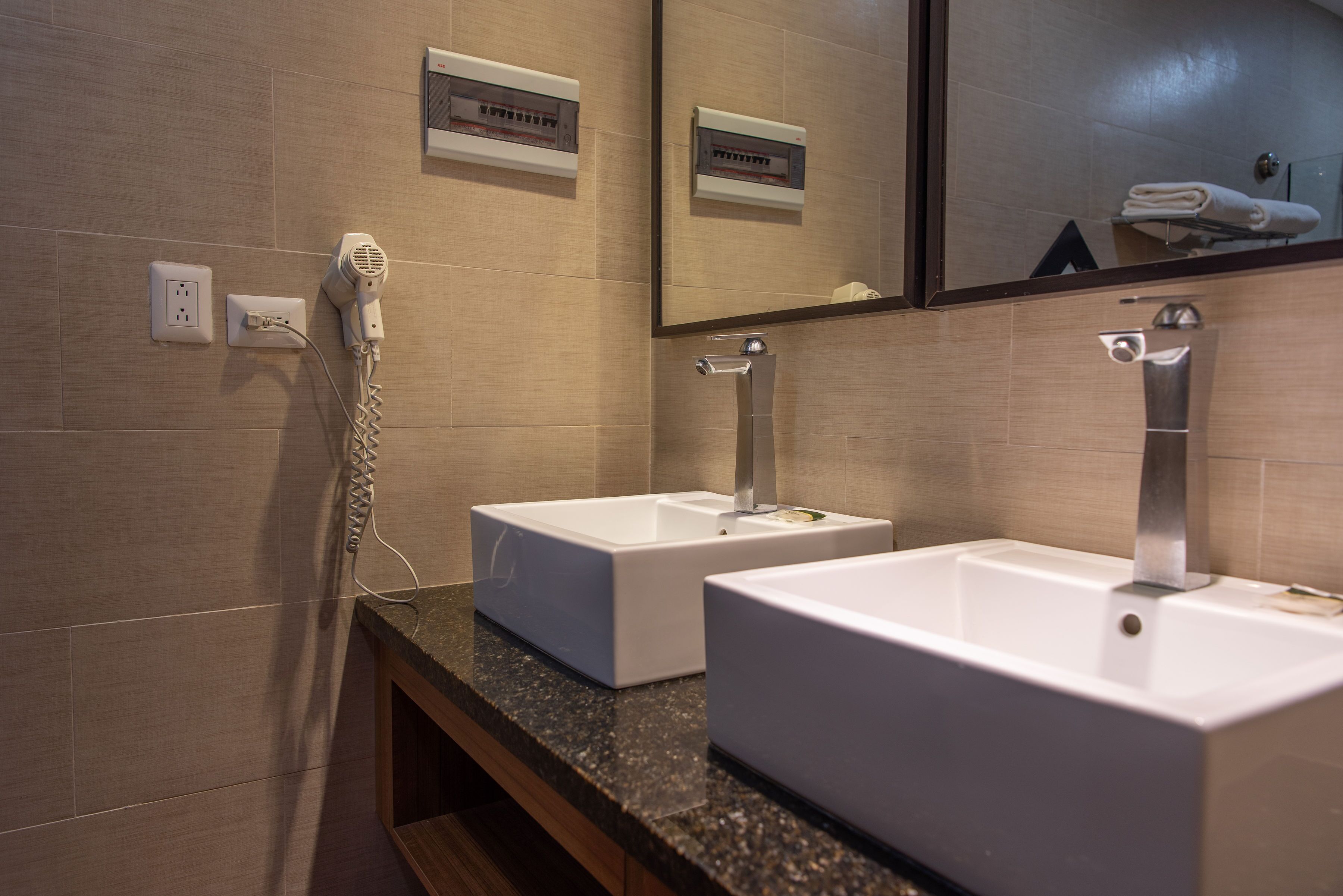 A bathroom with two white sinks, a hairdryer, and a mirror.